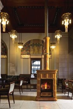 a large room with tables and chairs around a fire place in the middle of it