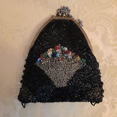 This is a gorgeous Art Deco glass beaded evening purse dating to the 1930s.   The evening purse is of a broadly triangular shape and is beautifully decorated with a background of shiny black glass beads with the centre of the purse highly decorated with a large golden basket of beautifully colourful flowers created from raised posies of brightly coloured glass beads.  The golden basket is created from many gold coloured glass beads and it glistens beautifully when it catches the light.  The two Deco Beads, Colourful Flowers, Metallic Purse, Art Deco Glass, Coloured Glass, Evening Purse, Small Mirrors, Beaded Bags, Bead Art