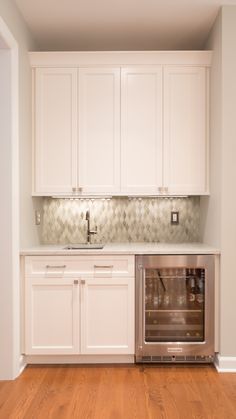 an empty kitchen with white cabinets and wood floors