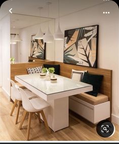 a dining room table with white chairs and a bench in front of the mirror on the wall