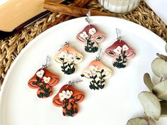 four earrings with flowers on them sitting on a plate