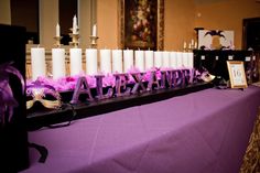 a table topped with candles and purple ribbons next to a sign that says alexend