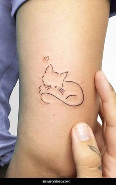 a cat tattoo on the back of a woman's left arm, with a heart in it