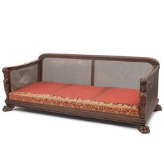 an old wooden couch with red cushions