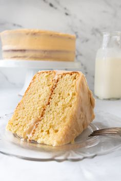 a slice of cake on a plate with a fork next to it and a bottle of milk in the background