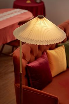 a table lamp sitting on top of a wooden floor next to a red couch in a living room