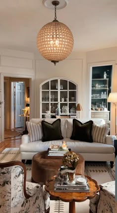 a living room filled with furniture and a chandelier hanging over the top of it