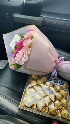 a bouquet of flowers and chocolates in the back seat of a car with a pink ribbon