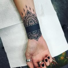 a woman's hand with a black and white tattoo design on it, holding onto her wrist