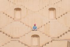 a person sitting on the side of a building made out of concrete blocks with holes in it