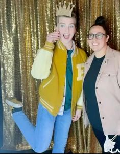 two people standing next to each other in front of a gold curtain with a crown on their head