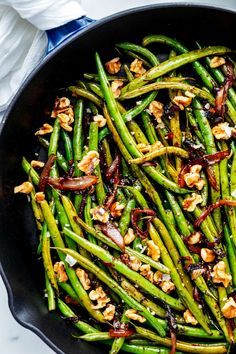 asparagus with walnuts and green beans in a skillet on a table