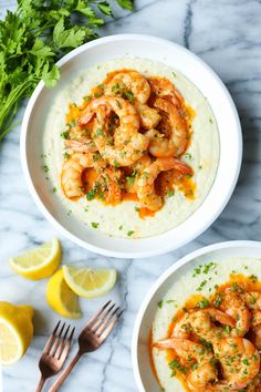 two white bowls filled with shrimp and grits on top of a marble countertop