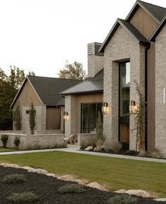 a large brick house with grass and bushes in the front yard on a cloudy day