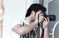 a man holding a camera up to his face and taking a picture in front of a door