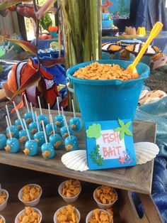 a table topped with blue cups filled with food and candy bars covered in candies