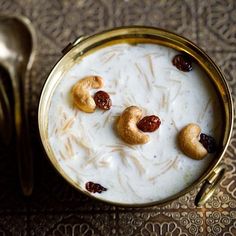 a bowl of oatmeal with nuts and raisins in it next to a spoon