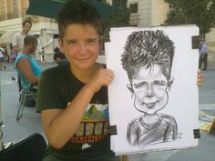 a young boy holding up a drawing of himself