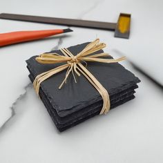 a stack of black slate coasters tied with twine and some orange handled scissors