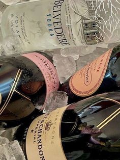 several bottles of wine sitting on top of ice covered rocks and paper wrapped around them