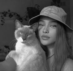 a woman wearing a hat holding a cat