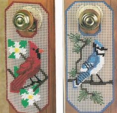 two cross stitch door hangers decorated with birds and daisies on wooden doors, one has a metal latch