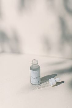 a small bottle of medicine sitting on top of a white table next to a dropper