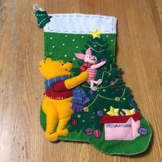 a winnie the pooh christmas stocking hanging on a wooden floor next to a teddy bear