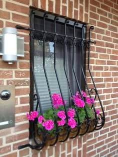 some pink flowers are sitting in a window sill on the side of a brick building