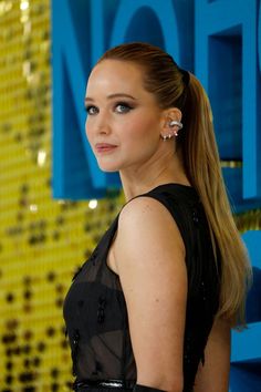 a woman with long hair and earrings on her head, wearing a black dress at an event