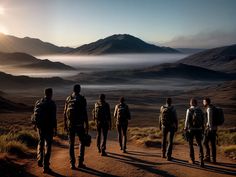 five men with backpacks are standing on a dirt road in front of the mountains