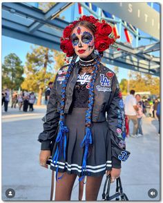 a woman with painted face and body art standing in front of a blue metal bridge