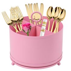 a pink container filled with gold colored utensils and a rose on the side