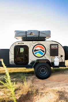 an rv parked on the side of a dirt road with its door open and luggage strapped to it