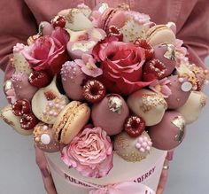 a person holding a box filled with macaroons and roses