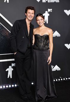 a man and woman standing next to each other on a black carpet at an event