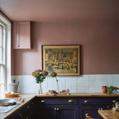 a painting hangs on the wall above a kitchen counter with dishes and utensils