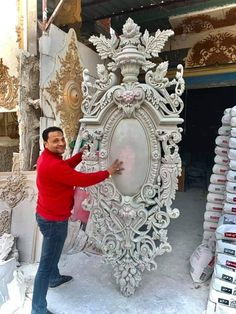 a man standing in front of a large white sculpture with ornate carvings on it's sides