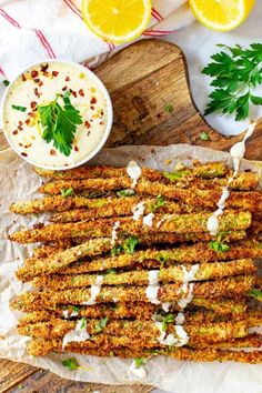 fried asparagus with parmesan sauce and lemon wedges on a cutting board