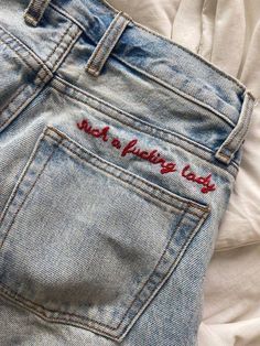 the back pocket of a pair of jeans with embroidered words on it and an open white shirt