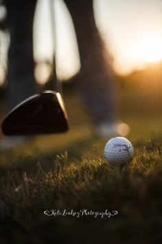 a golf ball sitting in the grass next to a driver's club at sunset