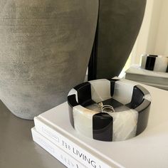 a couple of black and white bracelets sitting on top of a book next to a vase