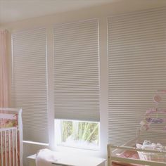 a baby's room with white blinds and pink crib in the foreground