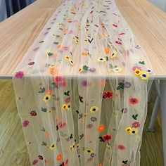 the table is covered with plastic and has colorful flowers on it, along with sheer curtains