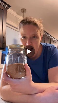 a woman holding a jar with something in it and making a funny face at the camera