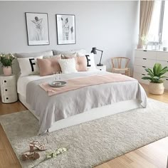 a bedroom with white and pink bedding, pictures on the wall and rugs