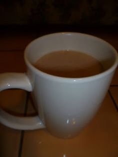 a white coffee cup sitting on top of a tiled floor