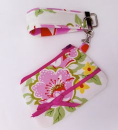 a pink and green flowered wristlet bag on a white background with a keychain