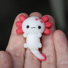 a hand holding a small white and red toy