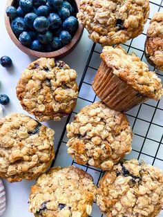 blueberry muffins on a cooling rack next to a bowl of fresh blueberries